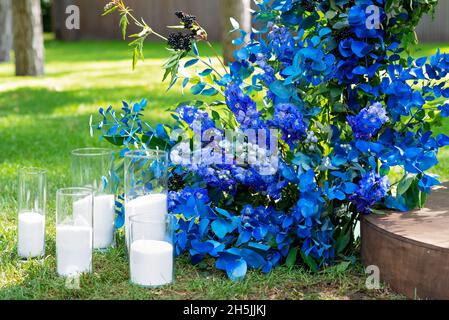 Bogen für eine Hochzeitszeremonie mit frischen Blumen in blau, und Kerzen, Nahaufnahme. Hochzeitsdekorationen. Weicher, selektiver Fokus. Stockfoto