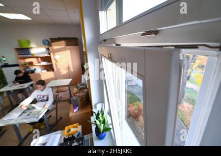 Naumburg, Deutschland. November 2021. Die Schüler der Käthe Kruse Schule in Naumburg sitzen in einem Klassenzimmer mit geneigtem Fenster. Das Burgenland hat 135 mobile Raumluftfilteranlagen und über 770 CO2-Ampeln für seine Schulen erworben. Die Investitionen hierfür beliefen sich auf über 600,000 Euro. Die Systeme sind seit Ende der Herbstferien in Betrieb und bieten zusätzlichen Schutz in Zeiten steigender Coronainfektionen. Quelle: Hendrik Schmidt/dpa-Zentralbild/dpa/Alamy Live News Stockfoto