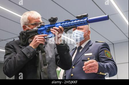 Sachsen, Schneeberg: Am 10. November 2021 erklärt Staatspolizeipräsident Horst Kretzschmar (r) dem sächsischen Finanzminister Hartmut Vorjohann (CDU) in der Polizeischule das halbautomatische Gewehr CR 223. Am selben Tag wurde auf dem Gelände ein moderner Schießstand in Betrieb genommen. In der 6.6 Millionen Euro teuren Anlage können mit Hilfe von Beamern und einem Bildschirm Schießübungen in einem Winkel von 180 Grad durchgeführt werden. Ziel der Schulung ist es, jedem Polizisten und jeder Polizistin zu ermöglichen, den sicheren Umgang mit Waffen zu üben und zu verinnerlichen. Die Schule in Schneeberg trainiert derzeit aroun Stockfoto