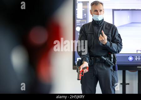 Sachsen, Schneeberg: Am 10. November 2021 zeigt Mathias Noetzig, Polizeihauptmann und Ausbilder, wie man in ihrem 1. Ausbildungsjahr an der Polizeitechnischen Schule zu Beginn des Dienstes mit der Dienstwaffe umgeht. Am selben Tag wurde auf dem Gelände ein moderner Schießstand in Betrieb genommen. In der 6.6 Millionen Euro teuren Anlage können mit Hilfe von Beamern und einem Bildschirm Schießübungen in einem Winkel von 180 Grad durchgeführt werden. Ziel der Schulung ist es, jedem Polizisten und jeder Polizistin zu ermöglichen, den sicheren Umgang mit Waffen zu üben und zu verinnerlichen. Die Schule in Schne Stockfoto