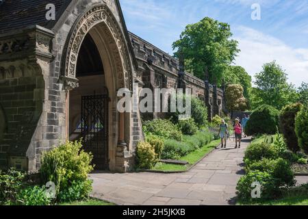 Ruhestand, Blick im Sommer auf ein aktives Seniorenpaar, das sich der Veranda der mittelalterlichen Holy Trinity Parish Church in Skipton, Yorkshire, England nähert Stockfoto