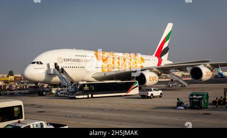 Dubai, VAE, 05.11.2021. Emirates Airbus A380-800 mit orangefarbener Expo 2020 Dubai-Lackierung an Bord von Passagieren am Dubai International Airport. Stockfoto