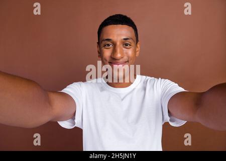 Foto von jungen fröhlichen afrikanischen Mann gute Laune schießen Selfie Urlaub isoliert über braunen Hintergrund Stockfoto