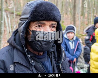 Narewka, Polen. November 2021. Ein älterer Mann aus Dohuk sah, wie er eine Schutzmaske im Wald trug.Eine siebzehnköpfige Flüchtlingsfamilie, darunter neun Kinder aus Dohuk, Irak, verbrachte siebzehn Tage in einem Wald an der polnischen Grenze von Belarus und wurde achtmal zurückgedrängt. Verzweifelt mit einem sieben Monate alten Baby und einer älteren Frau mit Beinproblemen beschlossen sie, Aktivisten um Hilfe zu bitten. Kredit: SOPA Images Limited/Alamy Live Nachrichten Stockfoto