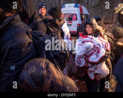 Narewka, Polen. November 2021. Eine junge Frau aus Dohuk wird nach einem Asylantrag in Polen zum Auto der polnischen Grenzschutzbeamten eskortiert.Eine siebzehnköpfige Flüchtlingsfamilie, darunter neun Kinder aus Dohuk, Irak, verbrachte siebzehn Tage in einem Wald an der Grenze zu Belarus - Polen und wurde achtmal zurückgeschoben. Verzweifelt mit einem sieben Monate alten Baby und einer älteren Frau mit Beinproblemen beschlossen sie, Aktivisten um Hilfe zu bitten. Kredit: SOPA Images Limited/Alamy Live Nachrichten Stockfoto