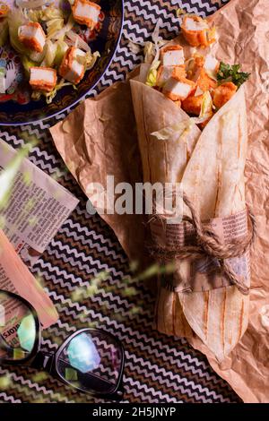 Frische Paneerrolle mit frischen Tomaten, Salat, Käse und Zwiebeln isoliert auf hellblauem Hintergrund. Top view.selective Fokus Stockfoto