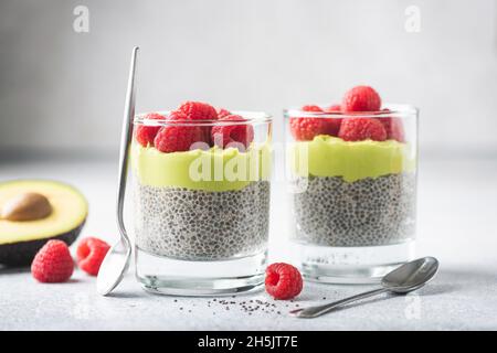 Veganer Avocado Chia Pudding mit Himbeeren auf grauem Betongrund. Gesundes Dessert reich an Omega-3-Fettsäuren Stockfoto