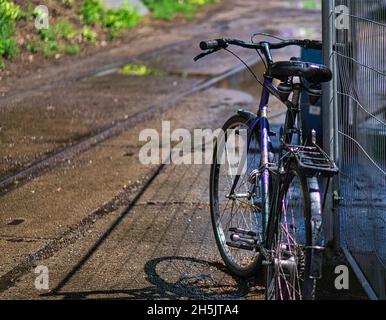 Geparktes Fahrrad an einem Bauzaun in Berlin. In der Hauptstadt werden Fahrräder an allen freien Plätzen geparkt. Stockfoto