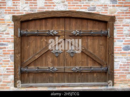 Halbkreisförmiges Holztor mit schmiedeeisernen Türknöpfen in einem Backsteingebäude. Alte Architektur Stockfoto