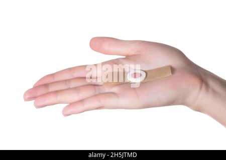 Die Hand einer Frau hält einen medizinischen Pflaster gegen die Kernkellen an den Fußsohlen. Nahaufnahme, Isolierung, Problem Stockfoto