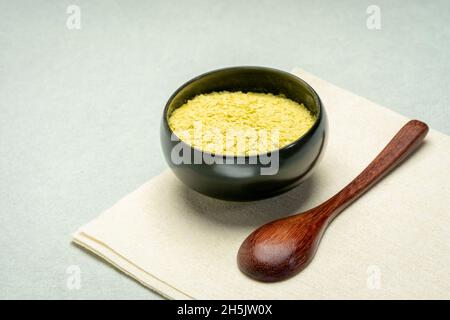 Ernährungsphysiologische Hefeflocken in einer kleinen Keramikschale mit einem hölzernen Teelöffel, Nahrungsergänzungsmittel, Backen und Kochen Stockfoto