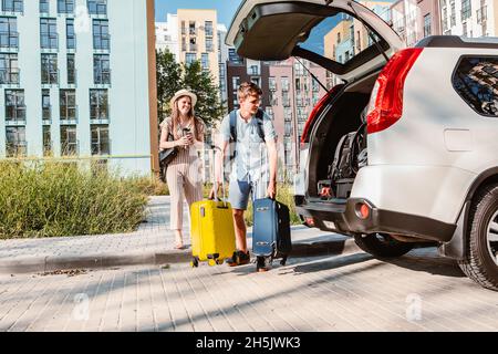 Paar sammeln für Road Trip. Putting Taschen auf Auto-Kofferraum. Sommerferien Stockfoto