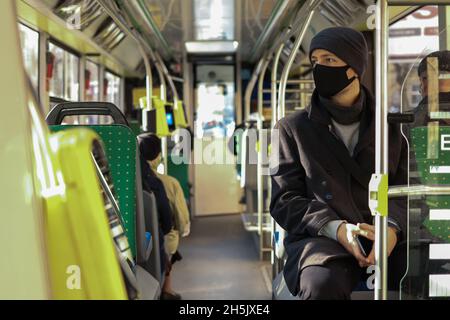 Mehrjähriger europäischer Mann mit Gesichtsmaske, der mit dem Bus in öffentlichen Verkehrsmitteln unterwegs ist Stockfoto