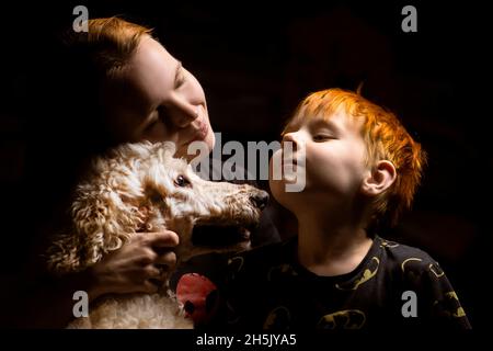 Mama mit einem jungen Sohn und einem Hund auf schwarzem Hintergrund. Stockfoto