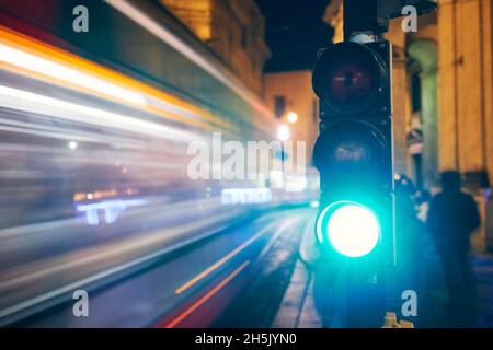 Grün auf Ampel gegen leichte Spuren von Straßenbahn und Autos. Nachtszene der Straße in Prag, Tschechische Republik. Stockfoto