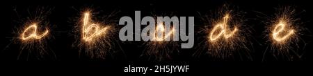 golden Bright Sparkler Alphabet Schrift Buchstaben Set Kollektion Teil A bis E isoliert auf dunkelschwarzem Hintergrund. silvester Neujahr Geburtstag und Feier Stockfoto