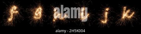golden Bright Sparkler Alphabet Schrift Buchstaben Set Kollektion Teil F bis K isoliert auf dunkelschwarzem Hintergrund. silvester Neujahr Geburtstag und Feier Stockfoto