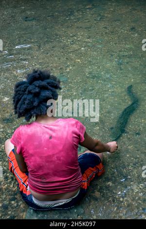 Frau füttert wilde Aale im Madang, Papua-Neuguinea; Madang, Provinz Madang, Papua-Neuguinea Stockfoto