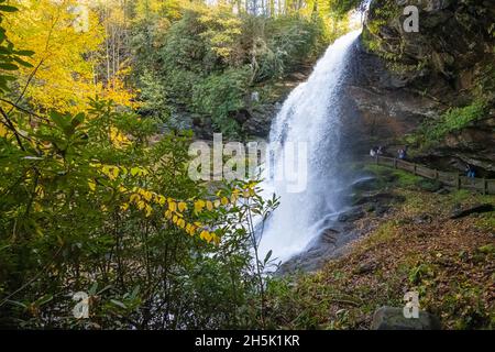 Besucher genießen die wunderschöne Herbstlandschaft bei Dry Falls, einem hinter dem Wasserfall zwischen Highlands und Franklin im Westen von North Carolina. (USA) Stockfoto