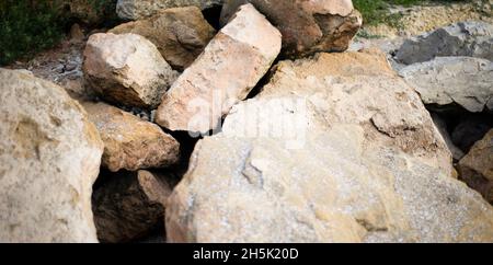 Steinhintergründe. Kopfsteinpflaster. Felsbrocken. Wellenbrecher. Große Steine an der Küste. Stockfoto