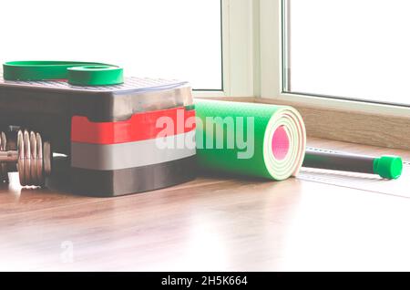 Ein Fitnessbestand befindet sich auf dem Boden in der Nähe des Fensters. Platz für Text Stockfoto