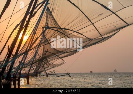 Traditionelle, ‘chinesische’ Fischernetze bei Sonnenuntergang in der Hafenmündung; Kochi, Kerala, Indien Stockfoto