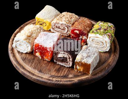 Türkisches Vergnügen. Eine Auswahl an türkischen Köstlichkeiten mit verschiedenen Geschmacksrichtungen, die mit Creme gefüllt sind. Lokum Rollen bedeckt Nüsse und Zuckerpulver auf Holz geschnitten Brett. Fr. Stockfoto