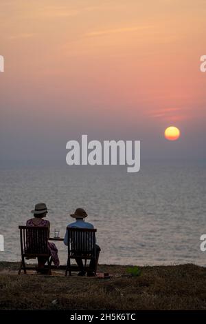 Gäste genießen einen Sonnenuntergang (Cocktails) auf einer Klippe über dem Boutique-Hotel Cabo Serai; Cabo, Goa, Indien Stockfoto