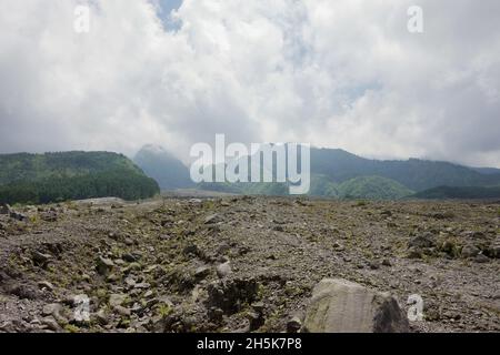 Mount Merapi Landschaft mit Wolken in blauem Himmel Hintergrund vom Bunker Kaliadem aus gesehen. Felsen und Materialien vom Vulkanausbruch 2010. Keine Personen. Stockfoto