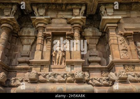 Nische mit hinduistischer Gottheitsschnitzerei in Steinmauer des Dravidischen Chola-Tempels der Airavatesvara-Ära mit Säulen und Reliefskulpturen Stockfoto