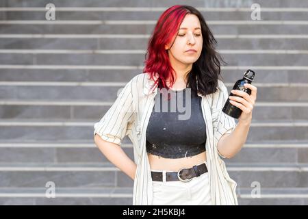 Porträt einer jungen, stilvollen Frau mit Öko-Flasche aus Stahl in der Hand, in legerer Kleidung Stockfoto