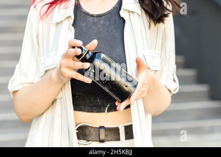 Nahaufnahme der weiblichen Hände mit wiederverwendbarer alter Edelstahlwasserflasche. Stockfoto