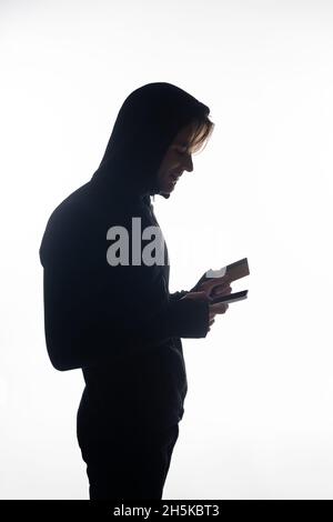 Seitenansicht des Hackers, der Handy und Kreditkarte hält, auf Weiß isoliert Stockfoto