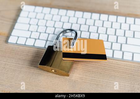 Nahaufnahme der Kreditkarte im Vorhängeschloss neben der Tastatur auf dem Holztisch Stockfoto