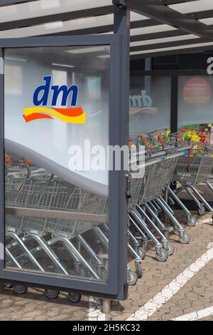 NEUWIED, DEUTSCHLAND - 20. Jun 2021: Neuwied, Deutschland - 20. Juni 2021: Logo dm auf einer verglasten Trennwand mit Warenkörben in einer Reihe. dm ist ein deutsches ret Stockfoto