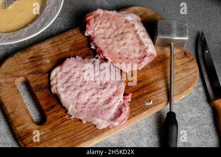 Zwei Stücke geschlagenen Fleisches auf einem Schneidebrett. Kochen von Schweinekoteletts. Stockfoto