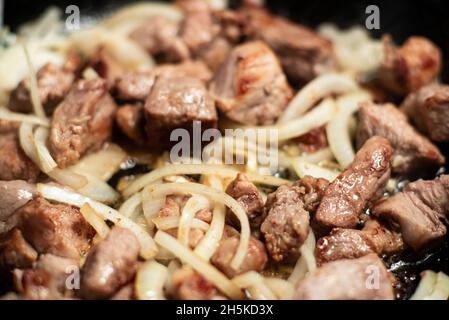 Gebratenes Fleischgulasch mit Karotten und Zwiebeln. Geschmortes Fleisch in einer Pfanne. Stockfoto
