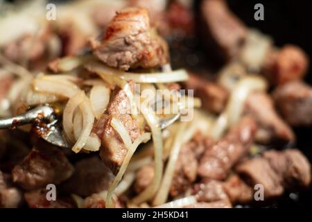 Gebratenes Fleischgulasch mit Karotten und Zwiebeln. Geschmortes Fleisch in einer Pfanne. Stockfoto