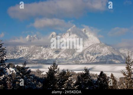 Schneebedeckte Grand Tetons im Grand Teton National Park mit blauem Himmel und tief liegenden Wolken; Wyoming, Vereinigte Staaten von Amerika Stockfoto