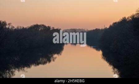 Bäume mit gefallenen Blättern am Ufer des Flusses Oka im Spätherbst bei Sonnenuntergang. Stockfoto