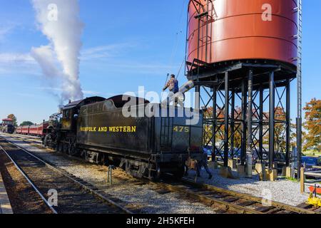 Strasburg, PA, USA - 7. November 2021: Ein Arbeiter auf der Strasburg Rail Road füllt den Wasserbehälter der Lokomotive, um Dampf zu machen. Stockfoto