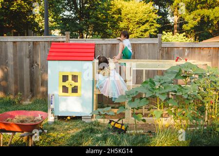 Im Sommer klettern zwei Kinder auf den Hühnerstall im Garten Stockfoto