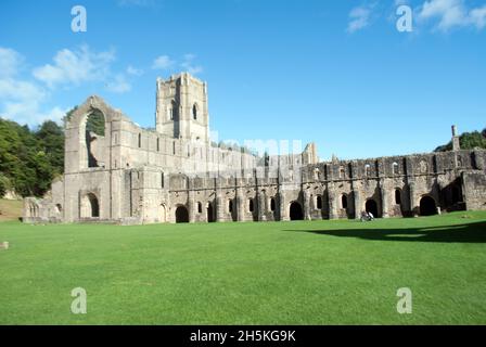 Menschen, die auf dem Gras vor dem Kirchenschiff und dem Großen Kreuzgang der Fountains Abbey, Aldfield, in der Nähe von Ripon, North Yorkshire, England, spazieren Stockfoto