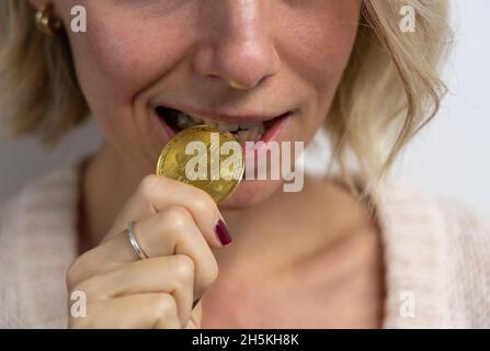 Bitcoins beißen und einer jungen Frau in die Augen stechen Stockfoto