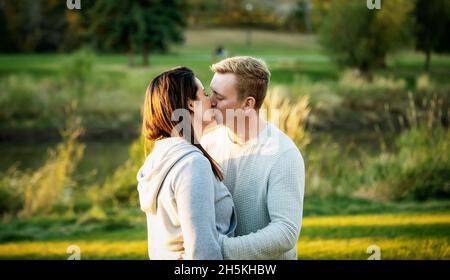 Ein mittelerwachsenes Paar, das bei Sonnenuntergang einen Kuss in einem Park teilt; St. Albert, Alberta, Kanada Stockfoto