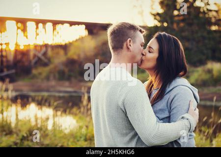 Ein Paar mit mittleren Erwachsenen, das im Herbst einen intimen Moment beim Sonnenuntergang in einem Park in St. Albert, Alberta, Kanada, genießt Stockfoto