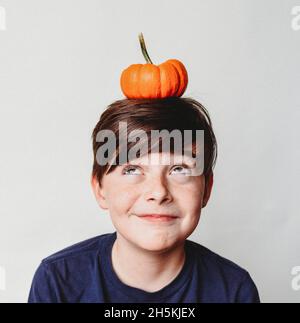 Porträt eines glücklichen Jungen mit einem kleinen Kürbis auf dem Kopf. Stockfoto