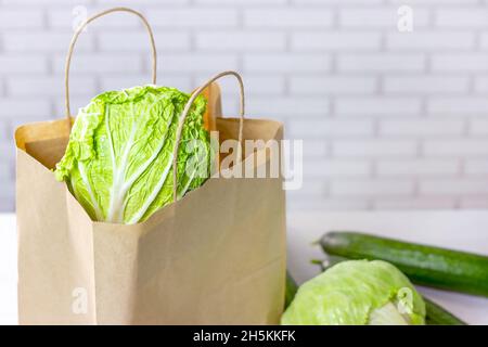 Bastelpapiertasche mit grünem Gemüse aus dem Online-Shopping nach Hause liefern in der Küche auf hellem Hintergrund mit Kopierraum. Stockfoto