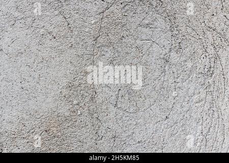 Dunkle Gipswand mit schmutzigem rissigem zerkratztem Hintergrund. Alte rissige verwitterte, schäbige Vintage-Ziegelwand im Retro-Stil mit schälen grauen Stuckstrukturen Stockfoto