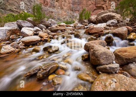 Ein schneller bewegender Bach fließt über die Wüste Felsen. Stockfoto